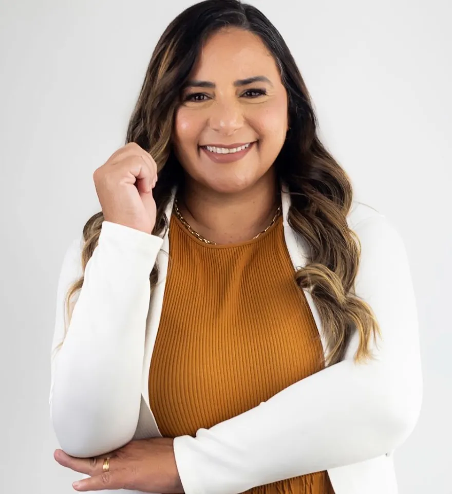 Dra. Patrícia Croucillo sorrindo, de blazer branco e blusa caramelo